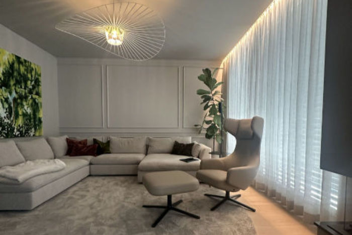 Die Eigentümer der im Bauhaus-Stil gekauften Villa wollten es gemütlicher, ohne einen Stilbruch zu begehen. Im Wohnbereich wurden deshalb Wände und Decke dezent getönt und mittels Wand Moulding strukturiert. Mit einem großen Teppich, weichen Vorhängen und mehreren indirekten Beleuchtungen wurde das Ziel erreicht. – Interior made by Katja A. Marocke